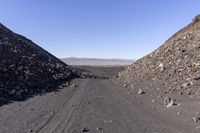 a group of rocks is sitting on a road, and the dirt is rocky and has dirted road and gravel behind it