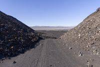 a group of rocks is sitting on a road, and the dirt is rocky and has dirted road and gravel behind it