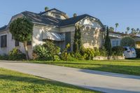 a house sitting on top of a lush green field of grass next to a sidewalk