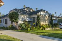 a house sitting on top of a lush green field of grass next to a sidewalk