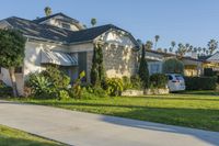 a house sitting on top of a lush green field of grass next to a sidewalk