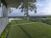 the large grassy garden is on a house deck with views of the city below it