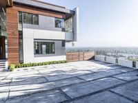 the exterior and landscape of a modern house in los angeles, california with stone and wood