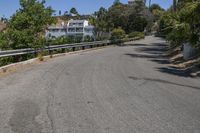 an empty road runs past a large white building in the distance, surrounded by trees and shrubs