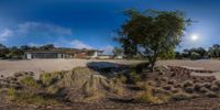 the panoramic view shows a modern looking home in an arid area with plants and shrubbery