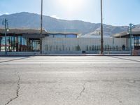 a paved sidewalk that is surrounded by buildings and a mountain range and a blue sky