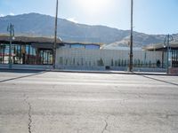 a paved sidewalk that is surrounded by buildings and a mountain range and a blue sky