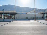 a paved sidewalk that is surrounded by buildings and a mountain range and a blue sky