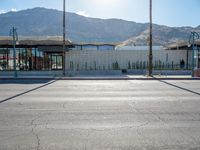 a paved sidewalk that is surrounded by buildings and a mountain range and a blue sky