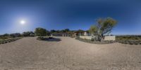 a big house sitting on top of a dirt lot with no grass around it and some trees