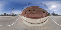 a fish - eye lens shot shows a red brick building on a corner with no parking