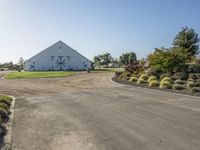 a farm and barn with lots of plants outside and the driveway next to it to the barn