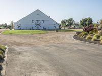 a farm and barn with lots of plants outside and the driveway next to it to the barn