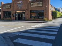 a brick building sits on the corner of an empty street with crosswalks and palm trees