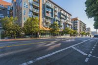 this is an empty city street with tall buildings in the background that are lined by trees