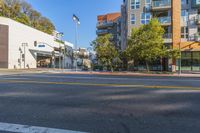 this is an empty city street with tall buildings in the background that are lined by trees