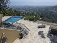 a tiled backyard with an open area and a plunge pool, surrounded by trees, and other buildings