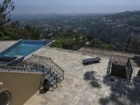 a tiled backyard with an open area and a plunge pool, surrounded by trees, and other buildings