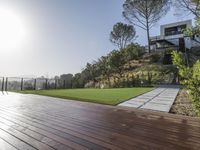 the wooden deck has grass and grass to provide privacy from the sun, and the landscaping also features plants, flowers, and shrubs