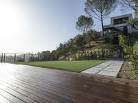 the wooden deck has grass and grass to provide privacy from the sun, and the landscaping also features plants, flowers, and shrubs