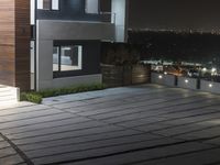 a concrete patio with planters on the sides of it at night overlooking a city