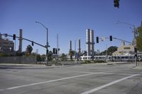 an empty street is near some factory smoke stacks and stop lights with a car coming to the top of it