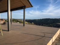 a covered patio with tables on the porch with a view of the woods and hills behind it