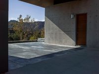 a gray concrete building with stairs and door at the top of the floor next to it is steps leading down to the doorway