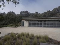 a garage with gray glass doors and a gravel path next to plants on the ground