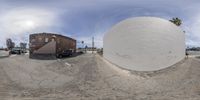 a fish eye view of a truck in the parking lot and on the road, two buildings are in a different view