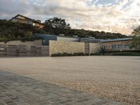 an outdoor concrete driveway with a large brick wall and wood fence to the side of the driveway