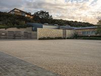 an outdoor concrete driveway with a large brick wall and wood fence to the side of the driveway