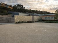 an outdoor concrete driveway with a large brick wall and wood fence to the side of the driveway