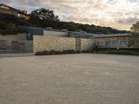 an outdoor concrete driveway with a large brick wall and wood fence to the side of the driveway