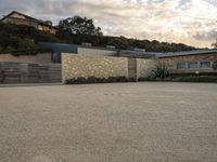 an outdoor concrete driveway with a large brick wall and wood fence to the side of the driveway