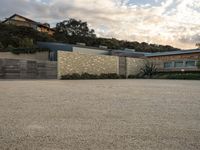 an outdoor concrete driveway with a large brick wall and wood fence to the side of the driveway