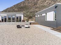 two gray homes with open spaces in the background and mountain side at the end of the building