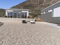 two gray homes with open spaces in the background and mountain side at the end of the building