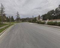 a road with trees and houses on either side of it in the distance is a house, tree - lined street