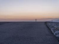 an empty street that is next to a rock wall and the water behind it is very clear