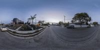 fisheye image of a street with buildings in the background and traffic at a stop sign