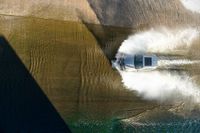 a boat driving through the ocean making waves on water in this aerial shot of the car being driven by the boat