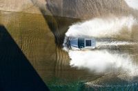 a boat driving through the ocean making waves on water in this aerial shot of the car being driven by the boat