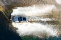 a boat driving through the ocean making waves on water in this aerial shot of the car being driven by the boat