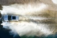 a boat driving through the ocean making waves on water in this aerial shot of the car being driven by the boat