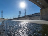 the sun shining over a section of the river running through an island area with power lines