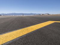 an empty airport runway in the desert with mountains in the background and a blue sky