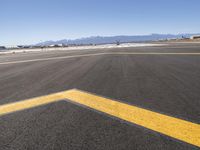 an empty airport runway in the desert with mountains in the background and a blue sky