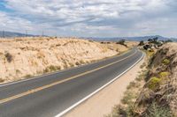 a road going down into the distance in the desert with a big sign on the other side