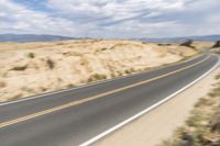a road going down into the distance in the desert with a big sign on the other side